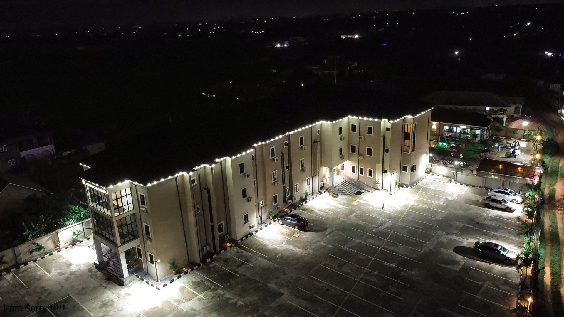 Aerial view of a multi-story building with exterior lights illuminating the parking lot at night.